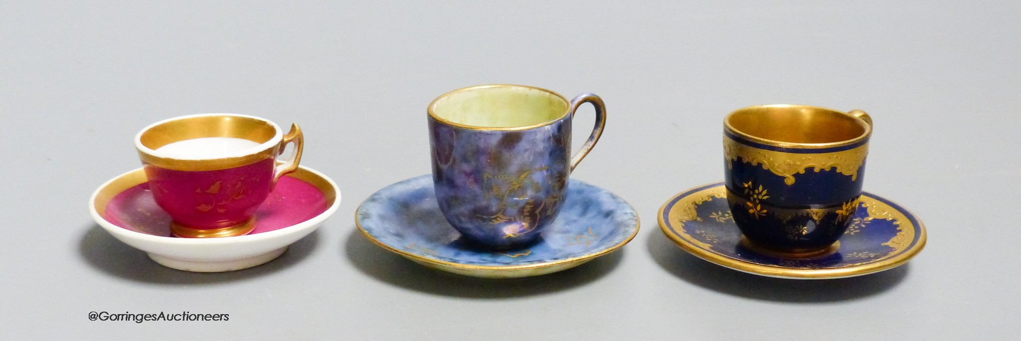 A Wedgwood lustre miniature cup and saucer with gilt decoration, a Coalport blue and raised gilt cup and saucer and a Grainger Worcester claret ground miniature teacup and saucer, tallest 3.5cm including saucer